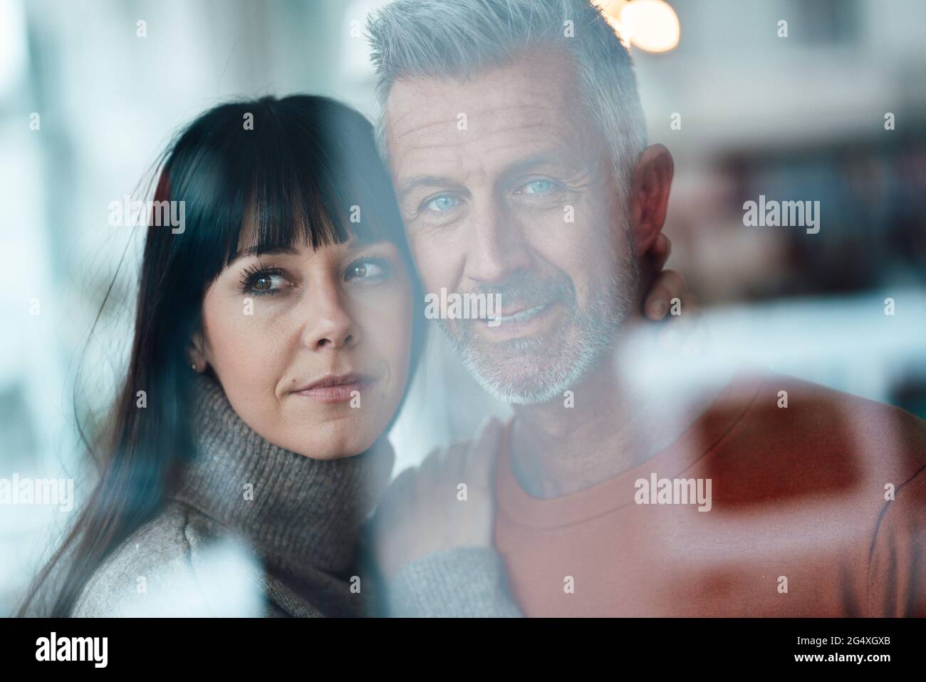 Femme mûre avec le bras autour de l'homme regardant loin au café Banque D'Images