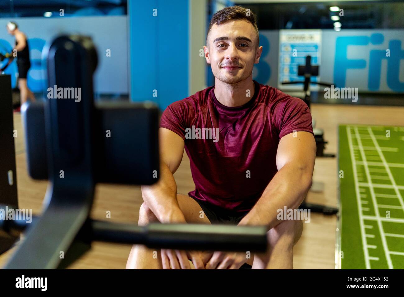 Beau athlète masculin assis sur l'équipement d'exercice à la salle de gym Banque D'Images