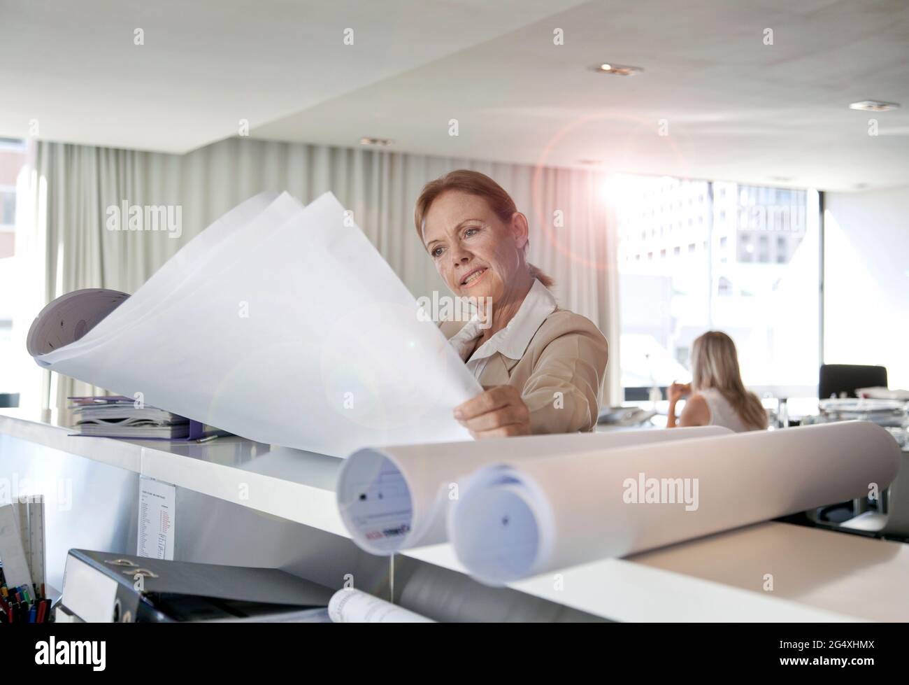 Businesswoman looking at blueprints in office Banque D'Images