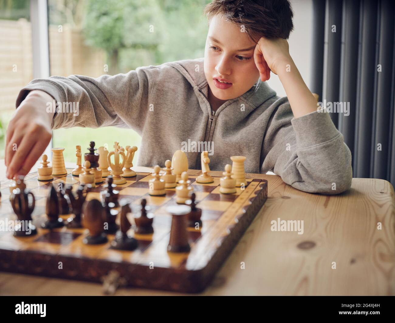 Un garçon intelligent jouant aux échecs à la maison Banque D'Images