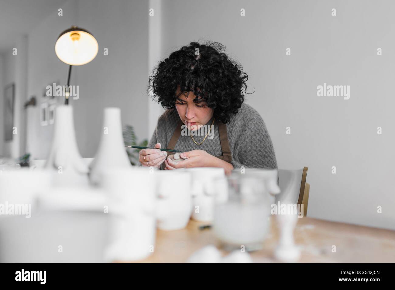 Femme artisan se concentrant tout en travaillant sur l'argile à l'atelier Banque D'Images