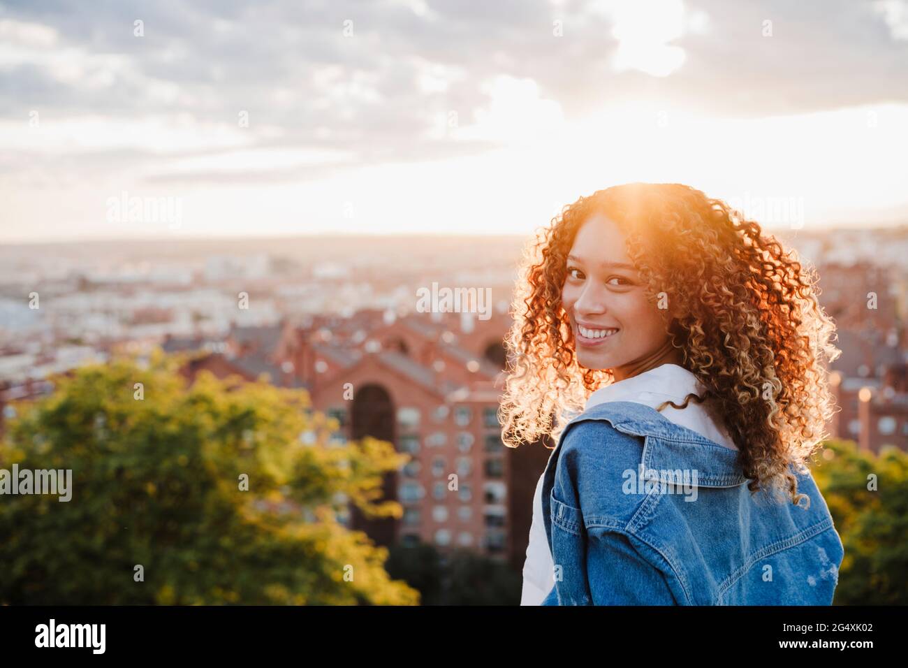 Jeune femme regardant sur l'épaule pendant le coucher du soleil Banque D'Images