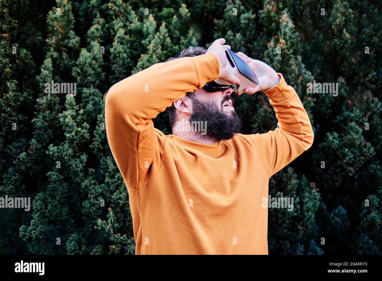 Homme mature portant un simulateur de réalité virtuelle dans le jardin Banque D'Images