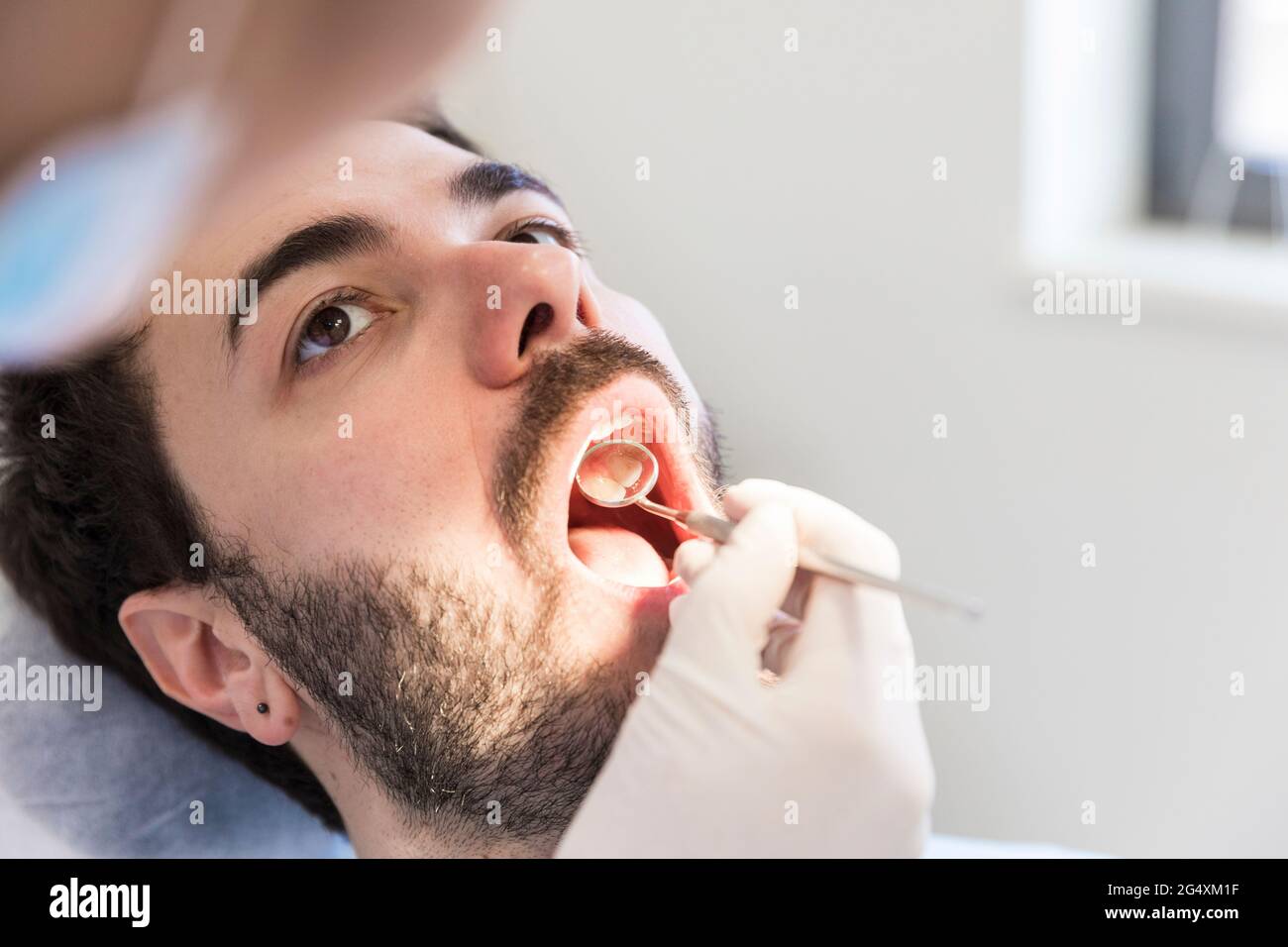 Dentiste féminin avec miroir incliné examinant les dents de la patiente à la clinique médicale Banque D'Images