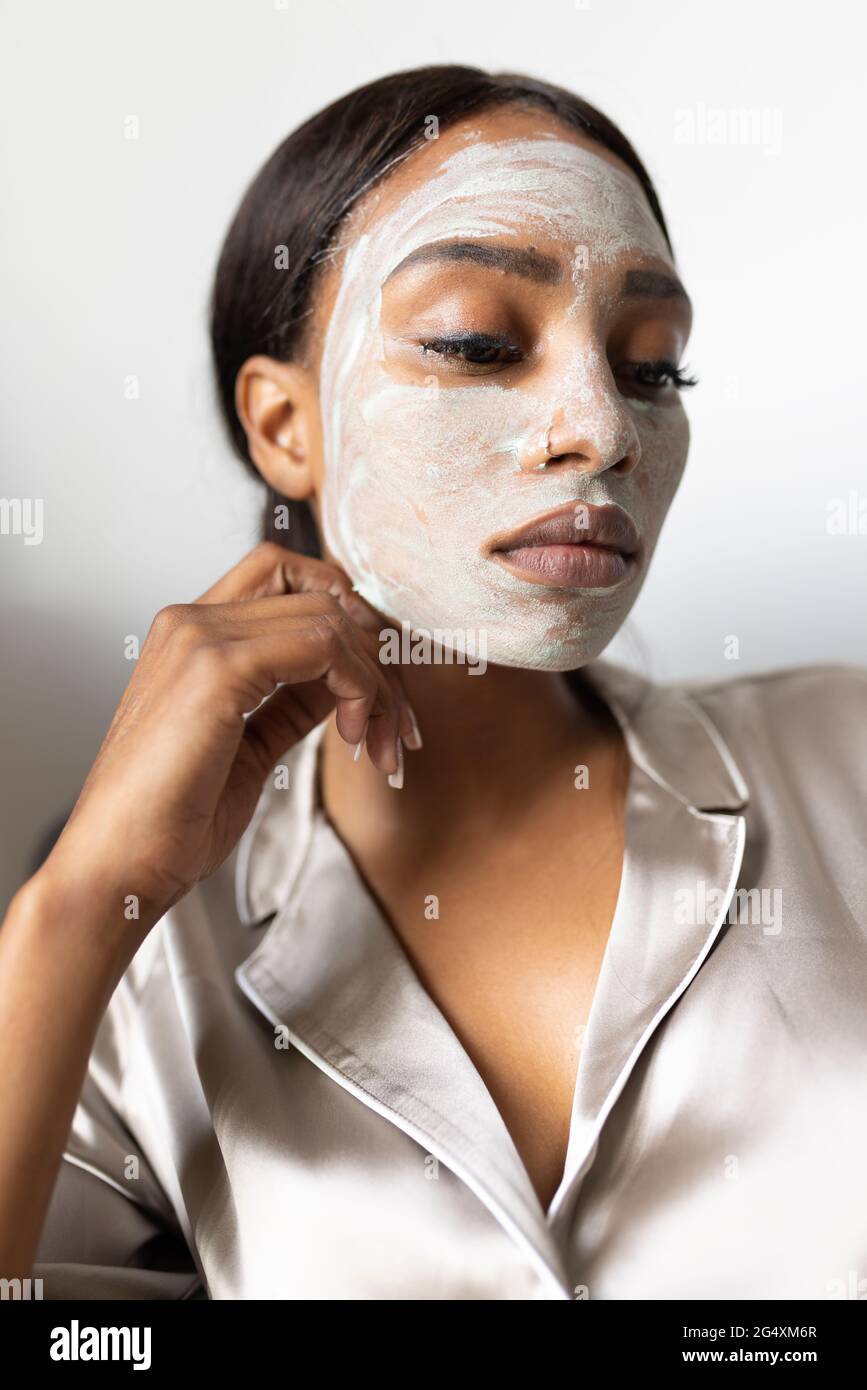 Jeune femme avec masque facial à la maison Banque D'Images