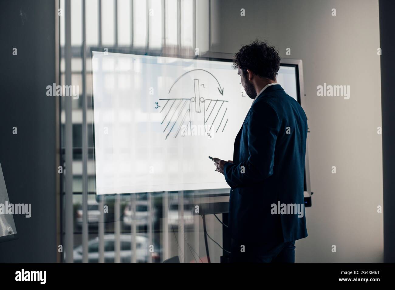 Homme entrepreneur brainstorming tout en se tenant près de l'écran de projection dans le bureau Banque D'Images