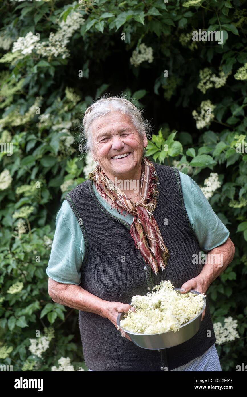 Joyeux fermier senior tenant des fleurs blanches dans un bol Banque D'Images