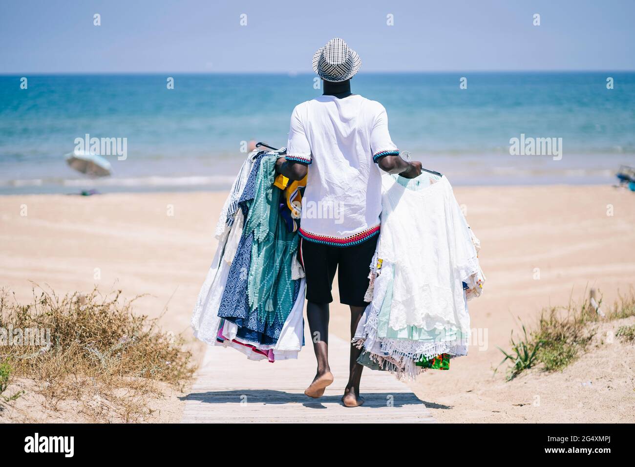 Fournisseur de robes à vendre marchant sur la promenade à la plage Banque D'Images