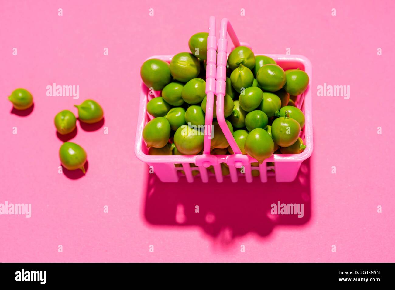 Photo de studio de petits pois verts crus dans un panier miniature Banque D'Images