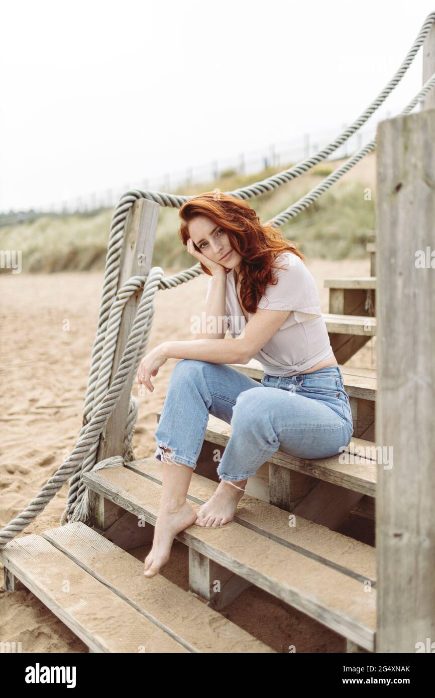 Femme assise sur des marches à la plage Banque D'Images