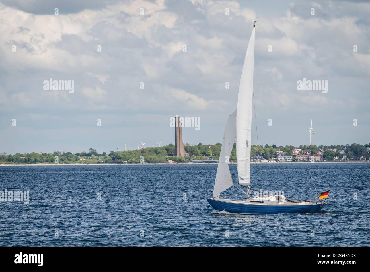 Allemagne, Schleswig-Holstein, Laboe, Lone voilier naviguant le long du fjord de Kiel avec le mémorial naval de Laboe en arrière-plan Banque D'Images