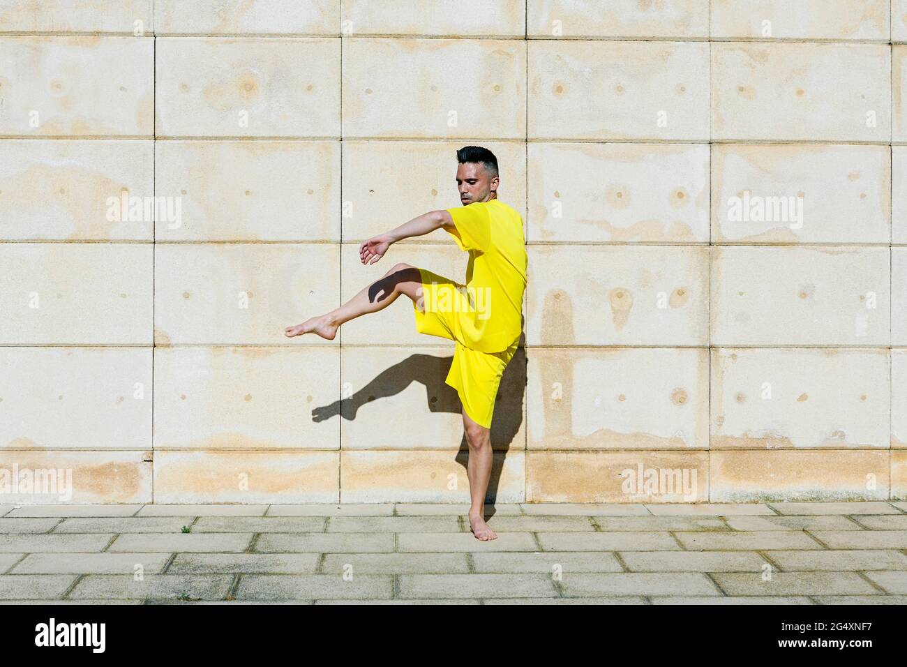Homme debout sur une jambe tout en dansant près du mur Banque D'Images