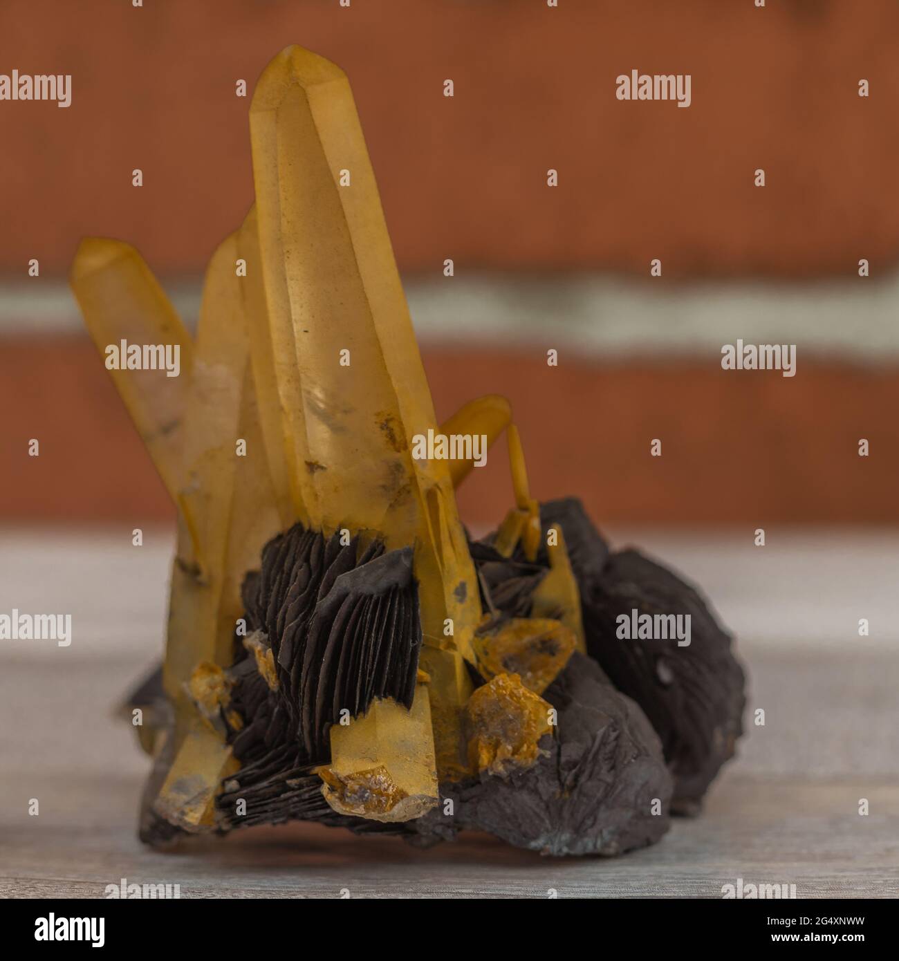 cristaux de quartz jaunâtres sur matrice avec fond de brique flou Banque D'Images