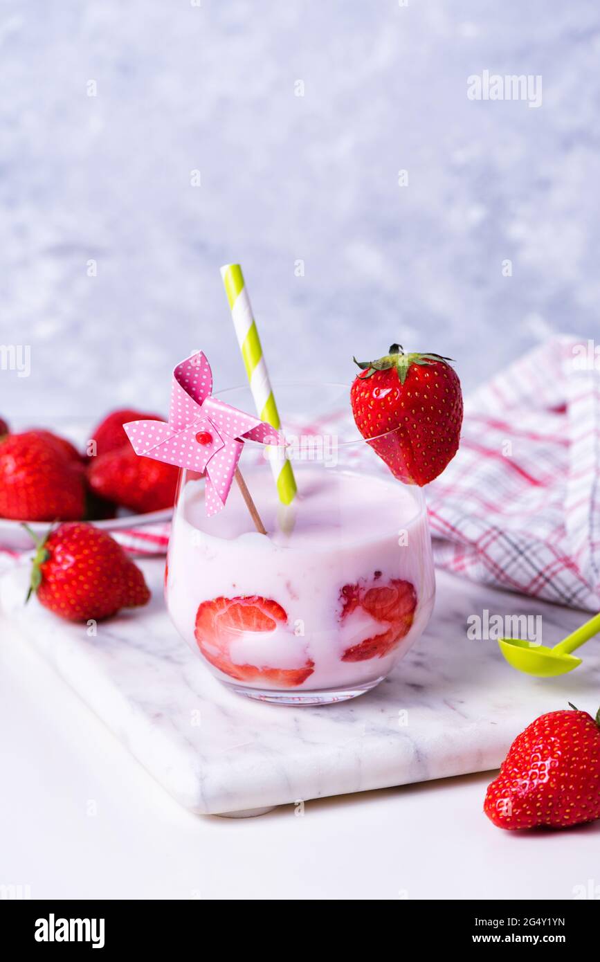 Un verre de yaourt à la fraise biologique fait maison avec des baies fraîches sur un plateau en marbre. Petit déjeuner sucré sain Banque D'Images
