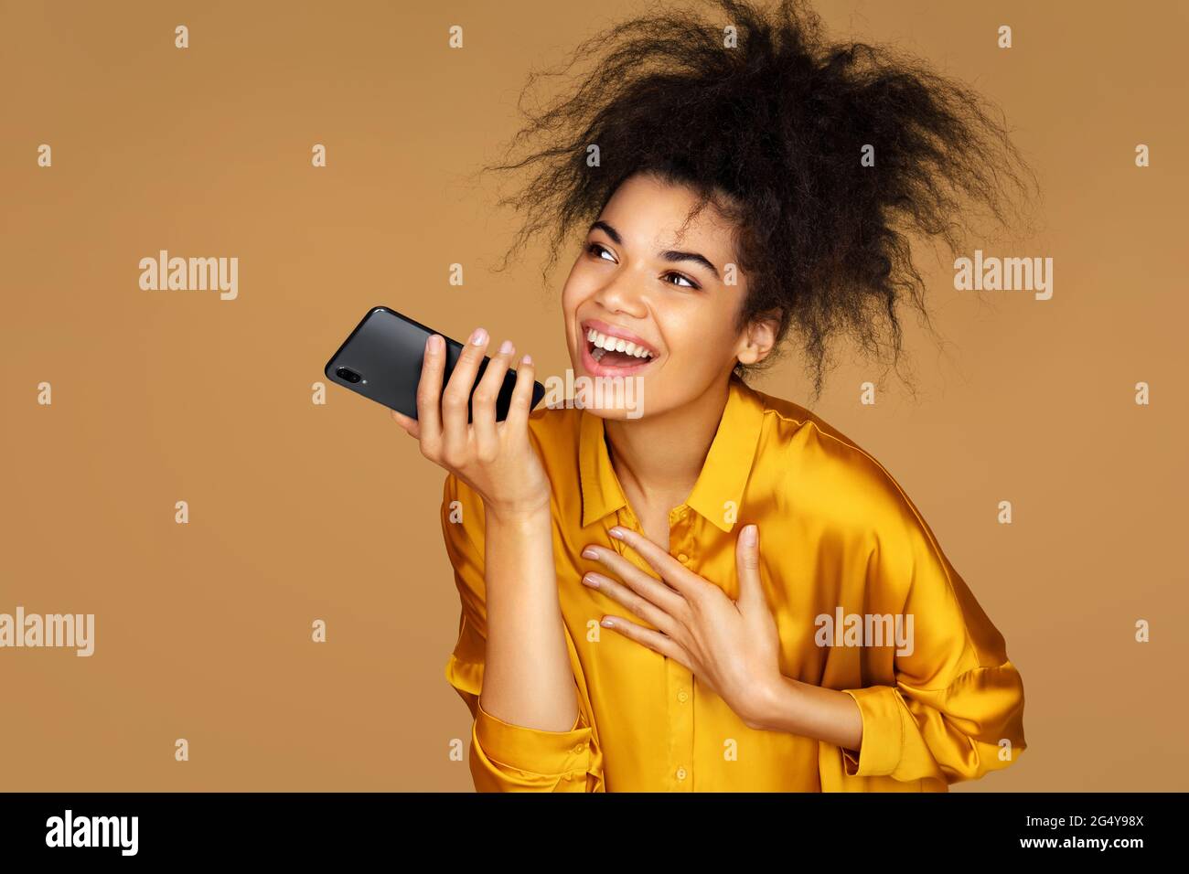 Fille utilise le téléphone, laisse un message vocal. Photo d'une fille afro-américaine sur fond beige Banque D'Images