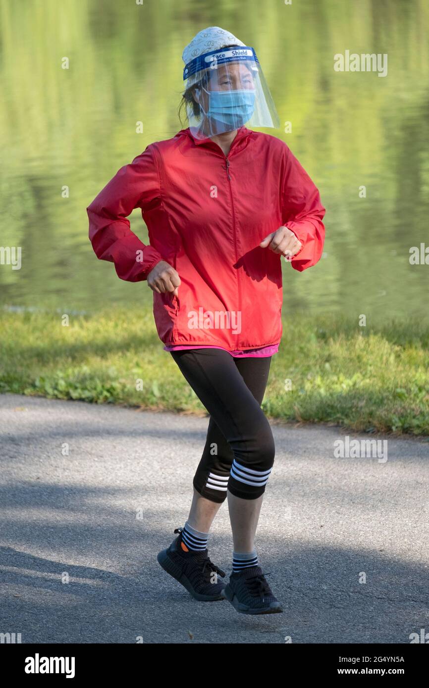 Une femme asiatique américaine, probablement chinoise, a fait une course tôt le matin en portant à la fois un masque et un masque facial. À Queens, New York. Banque D'Images