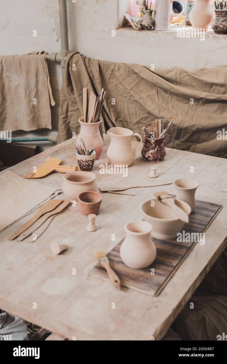 vue en grand angle des pots en argile faits à la main près de l'équipement sur une table en bois en poterie Banque D'Images