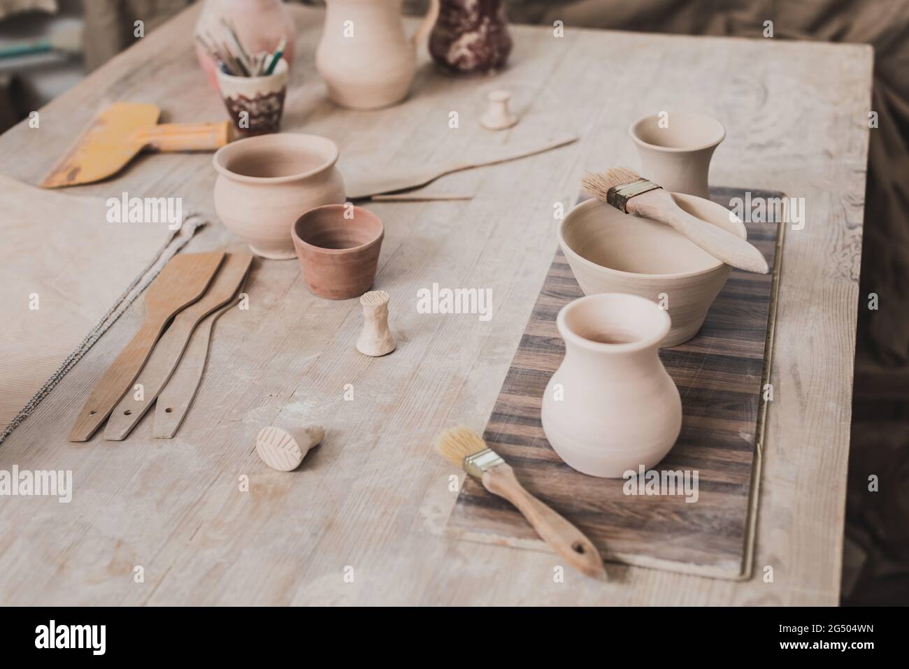 vue en grand angle des pots en argile faits à la main sur une table en bois près de l'équipement en poterie Banque D'Images