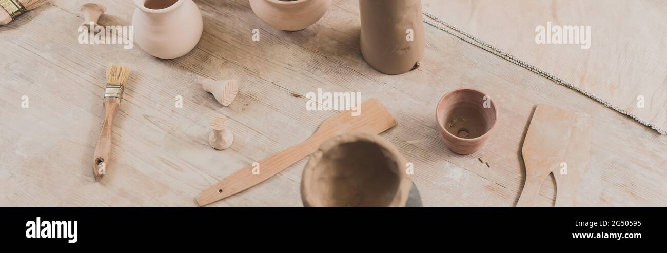 vue en grand angle des pots d'argile faits à la main avec spatules sur une table en bois en poterie, bannière Banque D'Images