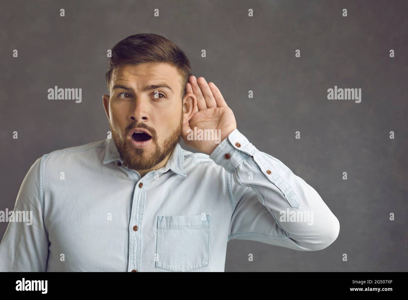 Curieux homme met main à l'oreille à l'écoute de nouvelles choquantes ou écoute sur le secret de quelqu'un Banque D'Images