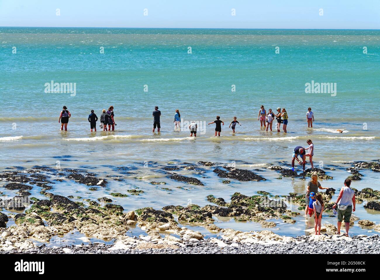 Les gens pagayent au bord de la mer sur la plage de Birling Gap lors d'une chaude journée d'été ensoleillée près d'Eastbourne East Sussex Angleterre Banque D'Images