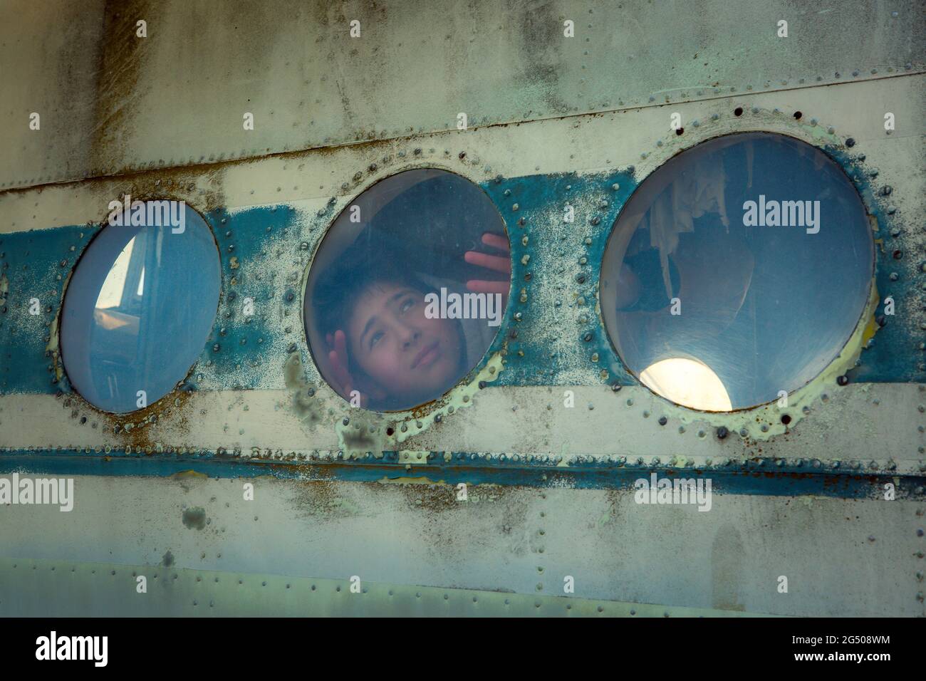 Un jeune homme à bord d'un ancien avion soviétique abandonné. Le gars regarde la fenêtre. Banque D'Images