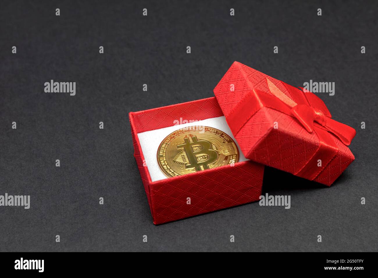 Cadeau BTC. Pièce de monnaie en bitcoin dans une boîte cadeau rouge sur  fond noir. Carte postale à imprimer, bannière avec emplacement pour le  texte Photo Stock - Alamy