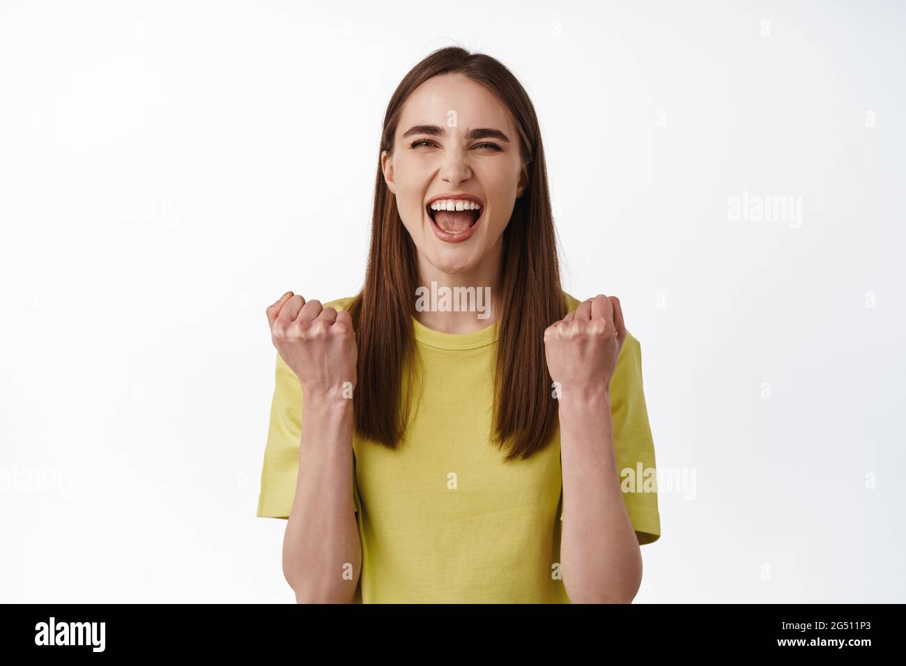 Oui, gagnant. Femme gagnante et chanceuse qui gagne, triomphant, criant pour la joie de la victoire, célébrant la victoire, se tenant joyeuse sur fond blanc Banque D'Images