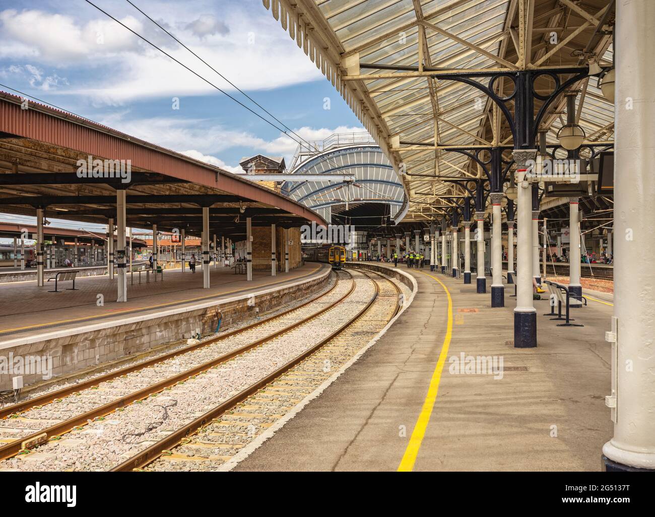 Vue typique d'une gare ferroviaire de la plate-forme avec un train en attente de départ. Une courbe très orné, métal et verre 19e siècle est couvert ci-dessus. Banque D'Images