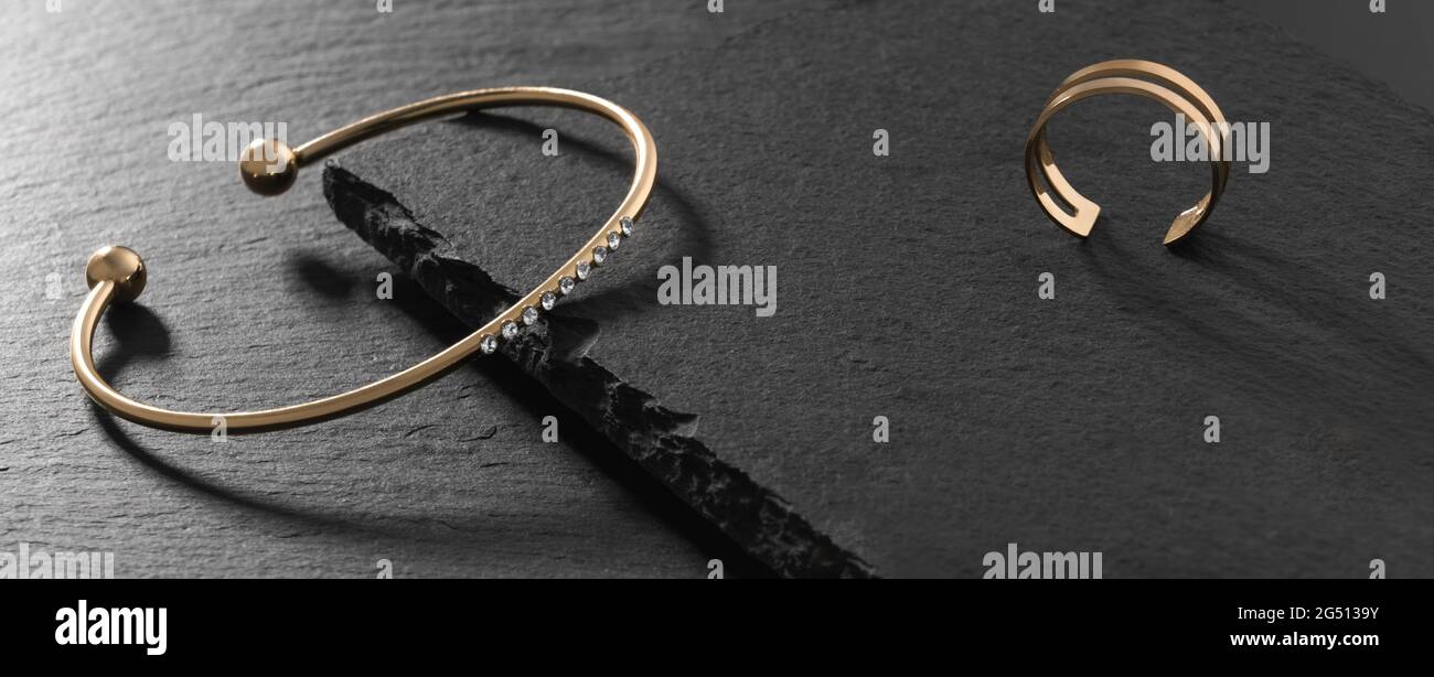 Bracelet moderne doré et anneau sur plaque en pierre noire Banque D'Images