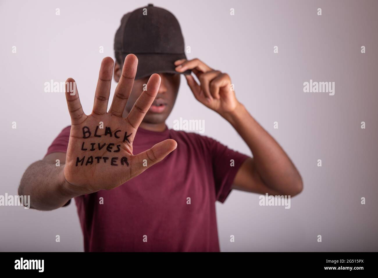 Gros plan de la main d'un Africain avec la citation « Black Lives Matter ».  Homme portant une casquette qui couvre ses yeux. Arrière-plan flou et  visage et paume de Photo Stock -