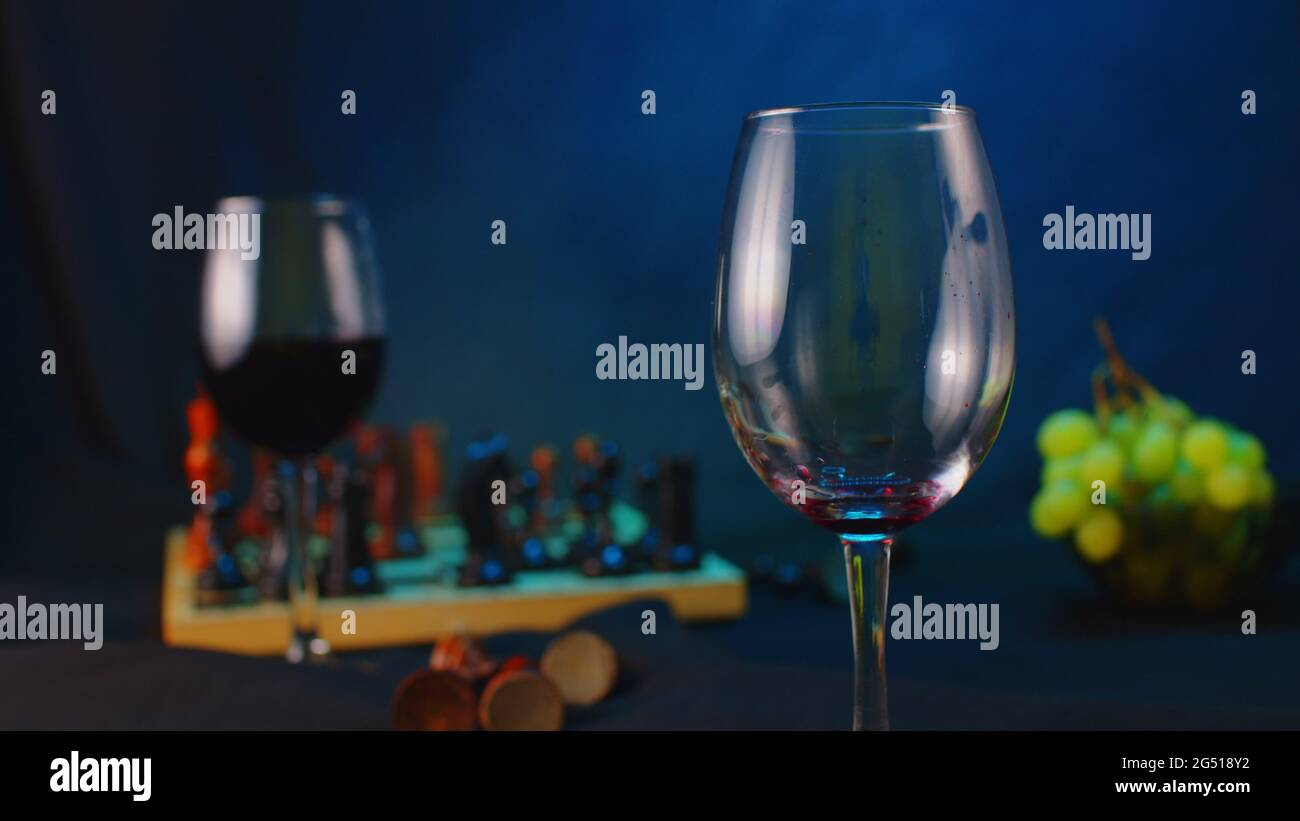 Gros plan d'un verre à vin vide sur fond noir avec éclairage et vapeur. Durée  de vie du verre vide en premier plan et du verre au vin rouge, à bord de