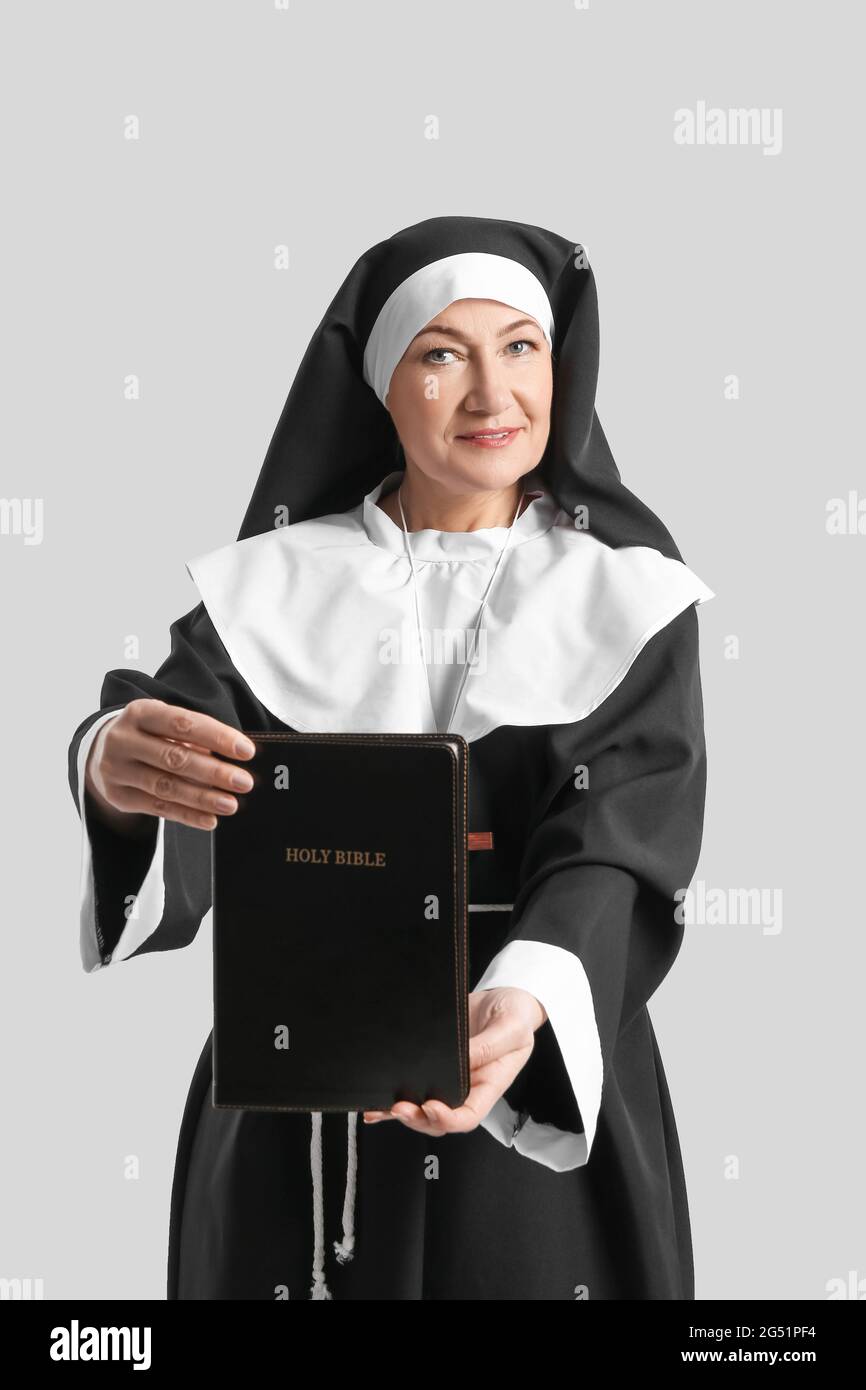 Nonne mature avec la Sainte Bible sur fond gris Photo Stock - Alamy