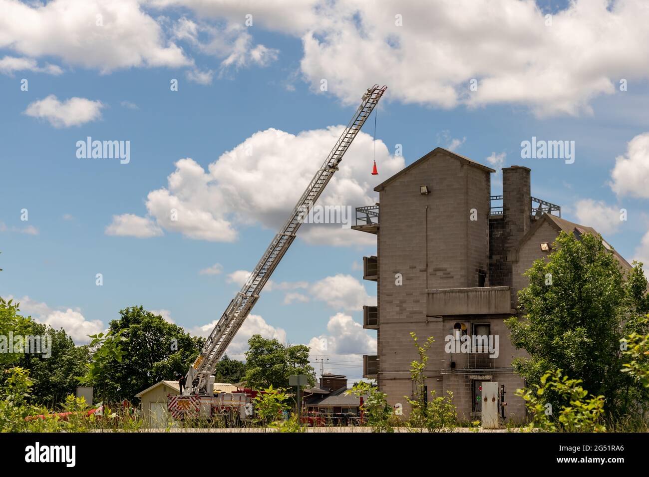 London, Ontario, Canada - juin 14 2021 : un pompier exploite une échelle pour essayer de placer un pylône orange sur un balcon de la tour d'entraînement à l'incendie. Banque D'Images