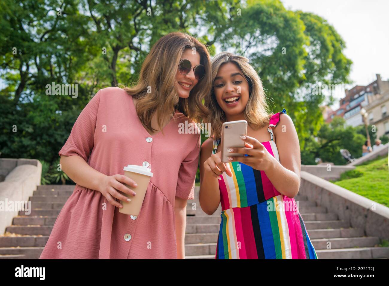 Deux amis utilisant un téléphone mobile à l'extérieur. Banque D'Images