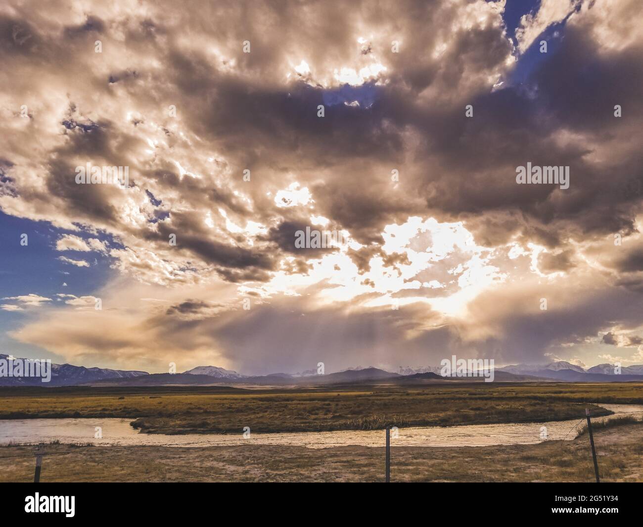 La rivière coule dans une plaine aride au ciel spectaculaire et dans les montagnes Banque D'Images