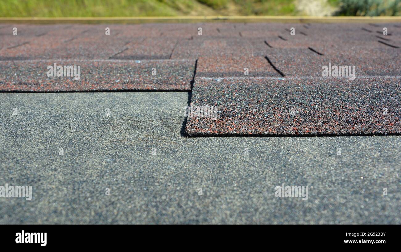 Installation de bardeaux de toiture en asphalte : gros plan sur l'asphalte architectural, bardeaux de toiture en bitume installés sur une sous-couche imperméable. Banque D'Images