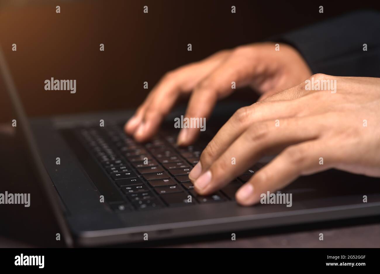 Les mains d'un homme d'affaires travaillant à la maison à l'aide d'un ordinateur portable, à l'intérieur, avec un foyer et un évasement sélectionnés. Banque D'Images