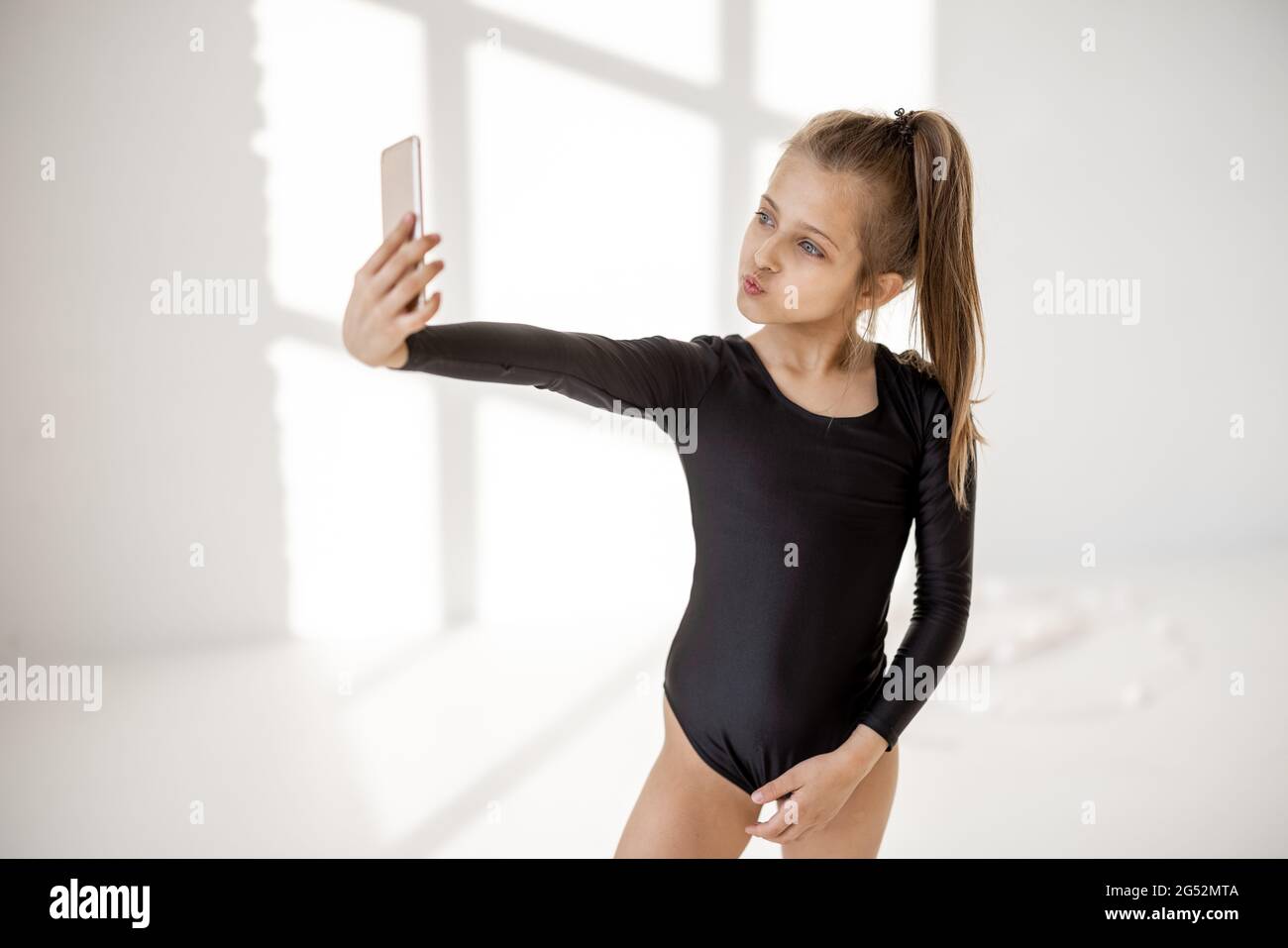 Petite fille assise avec un smartphone en cours de gymnastique Banque D'Images