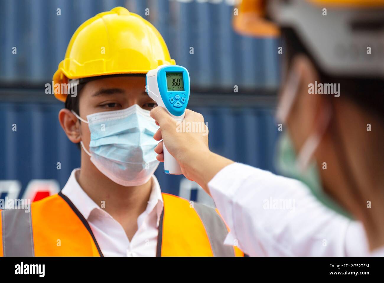 homme asiatique travailleur portant un masque de contrôle de la fièvre par thermomètre numérique avant d'entrer dans le travail pour protéger contre le covid, le covid-19 ou le coronavirus p Banque D'Images