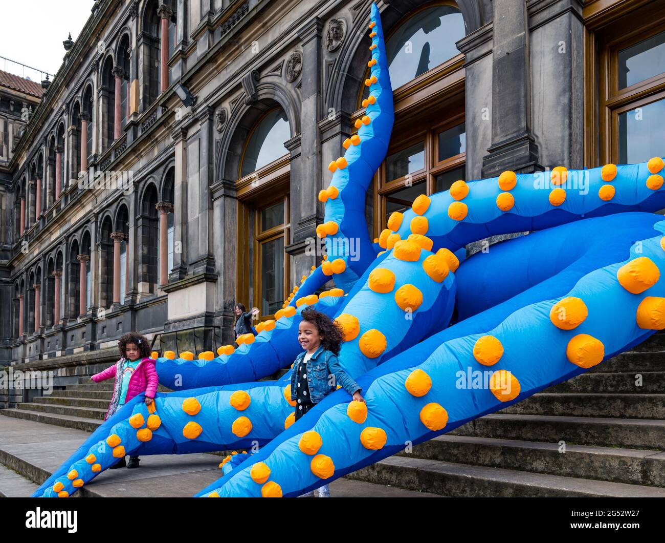 Édimbourg, Écosse, Royaume-Uni, 25 juin 2021. Lancement du Festival des sciences d'Édimbourg : le Festival des sciences d'Édimbourg 2021 (du 26 juin au 11 juillet) ouvre demain. Le 33ème Festival des sciences d'Édimbourg comprend une exposition interactive appelée Pale Blue Dot, qui présente des tentacules géants d'octopus au Musée national d'Écosse comme l'un des principaux points forts de cette année. Le thème du festival cette année est «un monde: La science nous connecte». En photo : Freya Simpson et Gabby, âgés de 5 ans, se battent avec les tentacules tandis que le poulpe sort du musée Banque D'Images