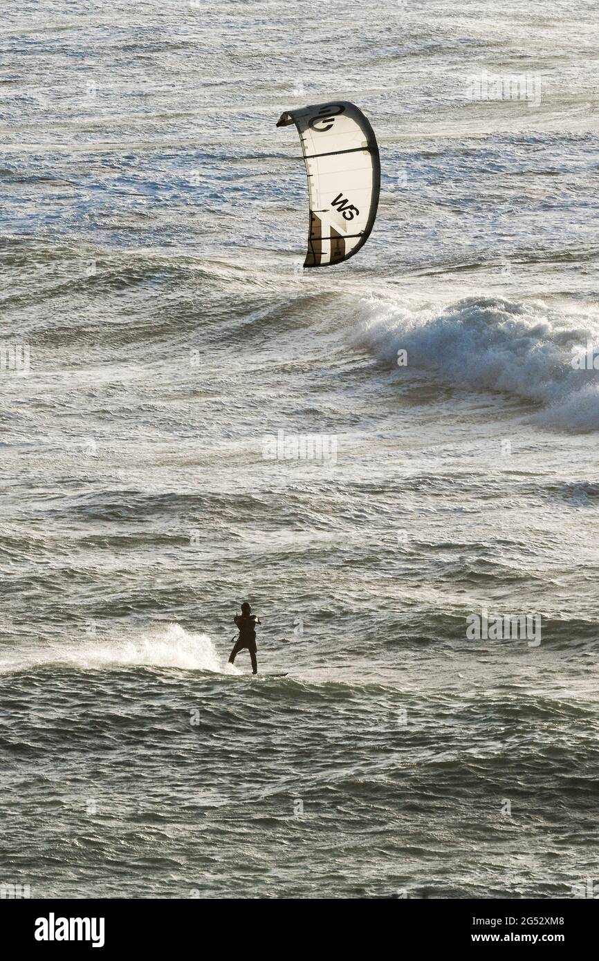 Un surfeur cerf-volant qui fait des vagues dans des vents violents à la plage de Crantock à Newquay, dans les Cornouailles. Banque D'Images