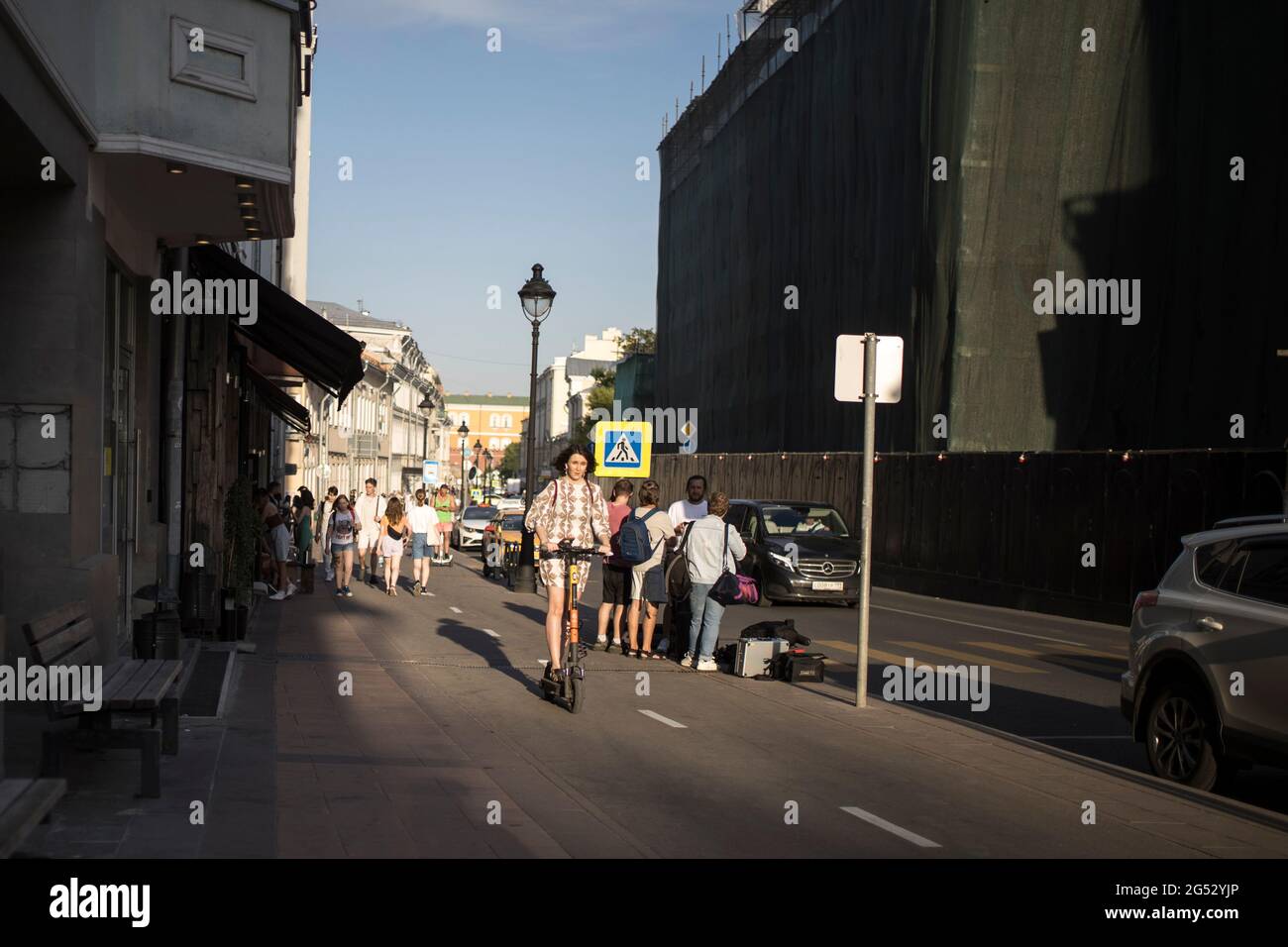 Moscou, Russie - 21 juin 2021, UNE fille de brune vêque d'un scooter électrique se déplace le long de la rue Bolshaya Nikitskaya le long d'une piste cyclable Banque D'Images