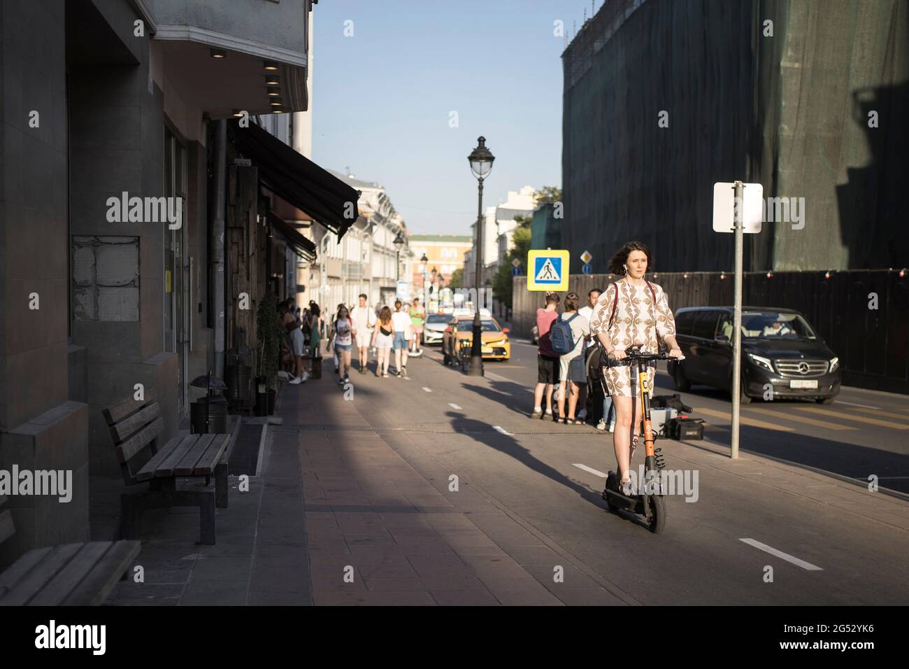 Moscou, Russie - 21 juin 2021, UNE fille de brune vêque d'un scooter électrique se déplace le long de la rue Bolshaya Nikitskaya le long d'une piste cyclable Banque D'Images