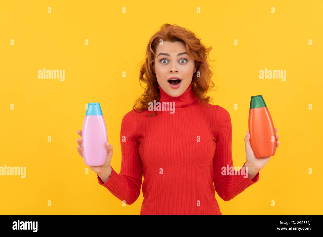 surprise redhead fille richement teint cheveux choisissant le produit de soins du corps de bouteille de shampooing, coiffeur Banque D'Images