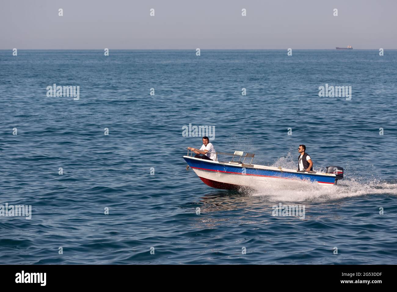 Deux personnes sur un petit bateau équipé d'un puissant moteur Yamaha naviguant rapidement près de la côte. Vue latérale. Rumelifeneri, Istanbul / Turquie. Banque D'Images