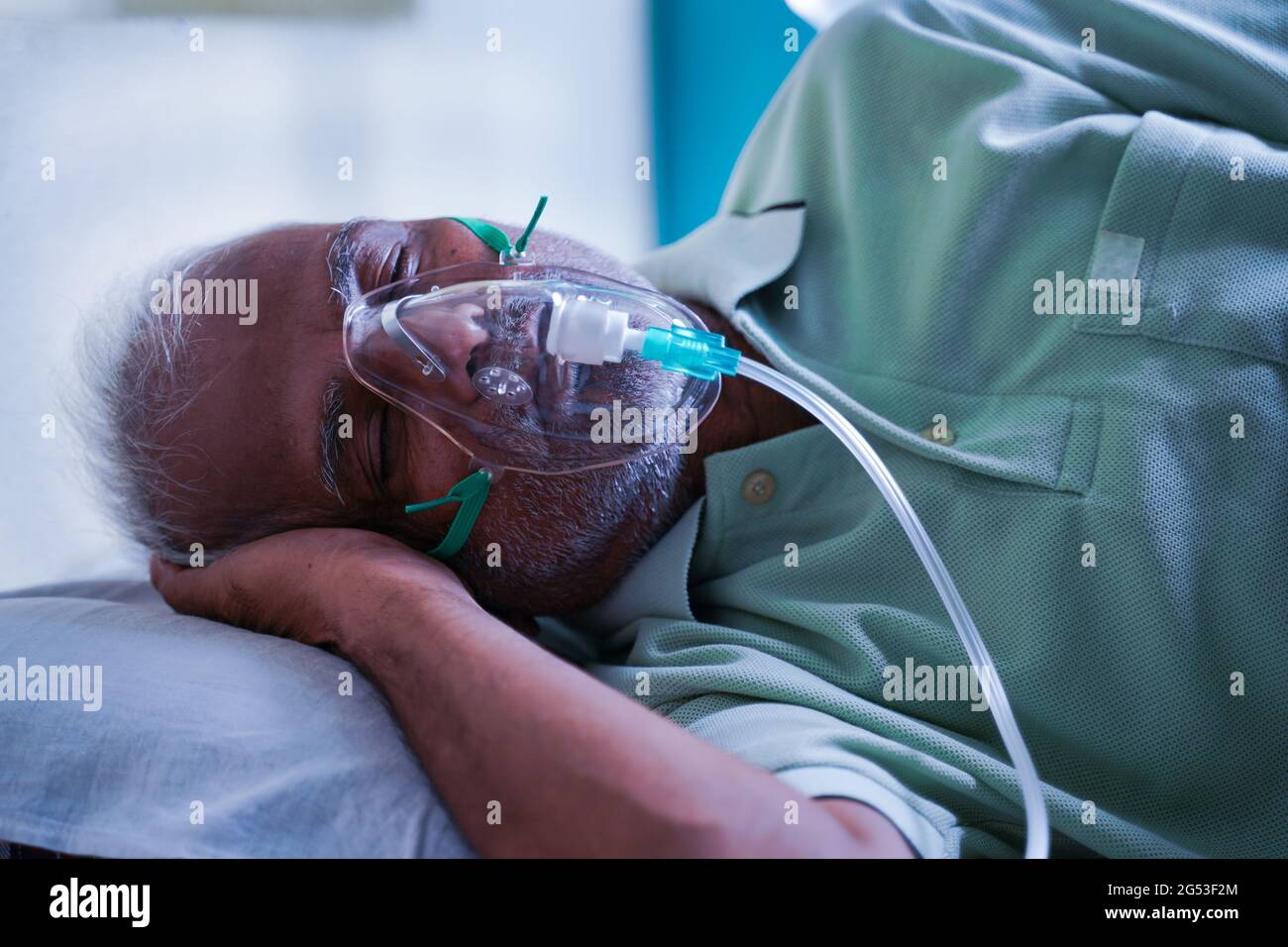 Vue latérale d'un patient âgé souffrant d'une respiration sur un masque de ventilation à oxygène en raison d'une infection virale à coronavirus ou à l'essoufflement Covid-19 à l'hôpital Banque D'Images