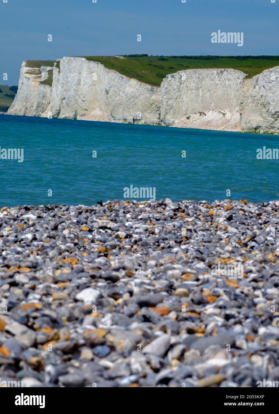 Idée de Staycation. Les falaises côtières à la craie blanche de Seven Sisters, à côté de la Manche à Birling Gap, avec une plage de galets en premier plan. Angleterre Banque D'Images