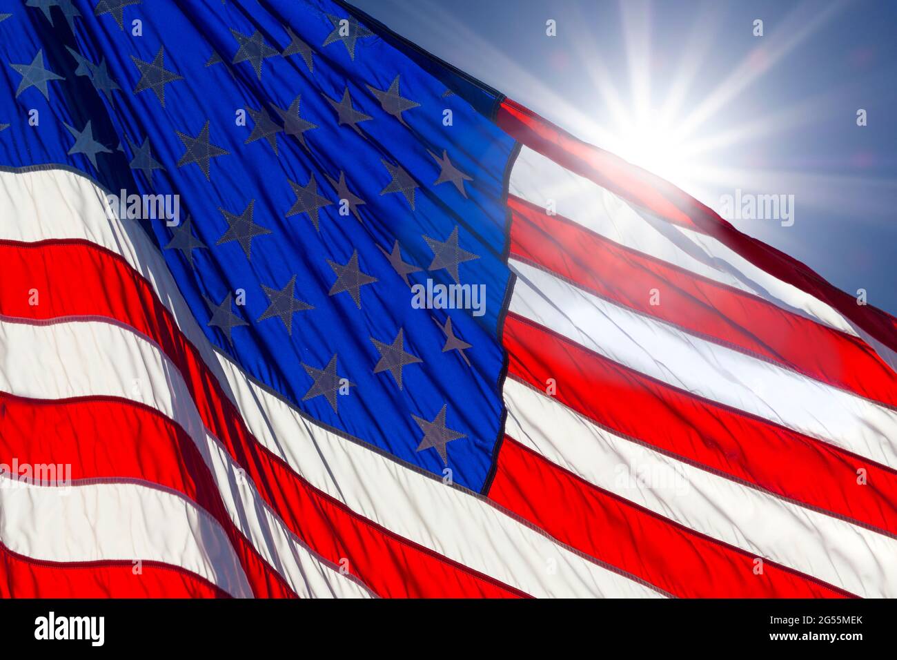 Le soleil se cache derrière le drapeau américain dans un ciel bleu Banque D'Images