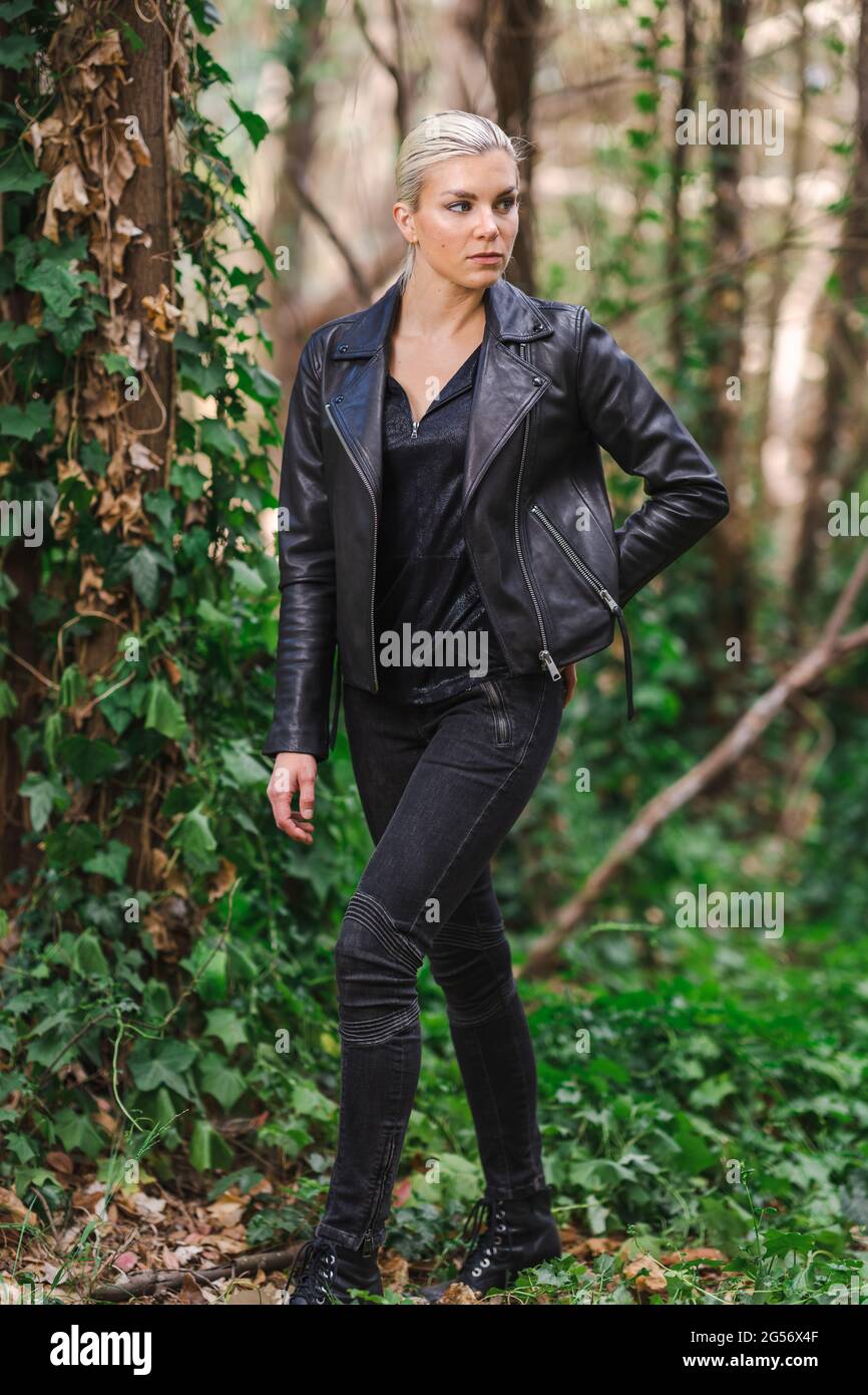 La mode dans des endroits insolites, jeune femme dans la veste de moto ébougée dans la forêt Banque D'Images